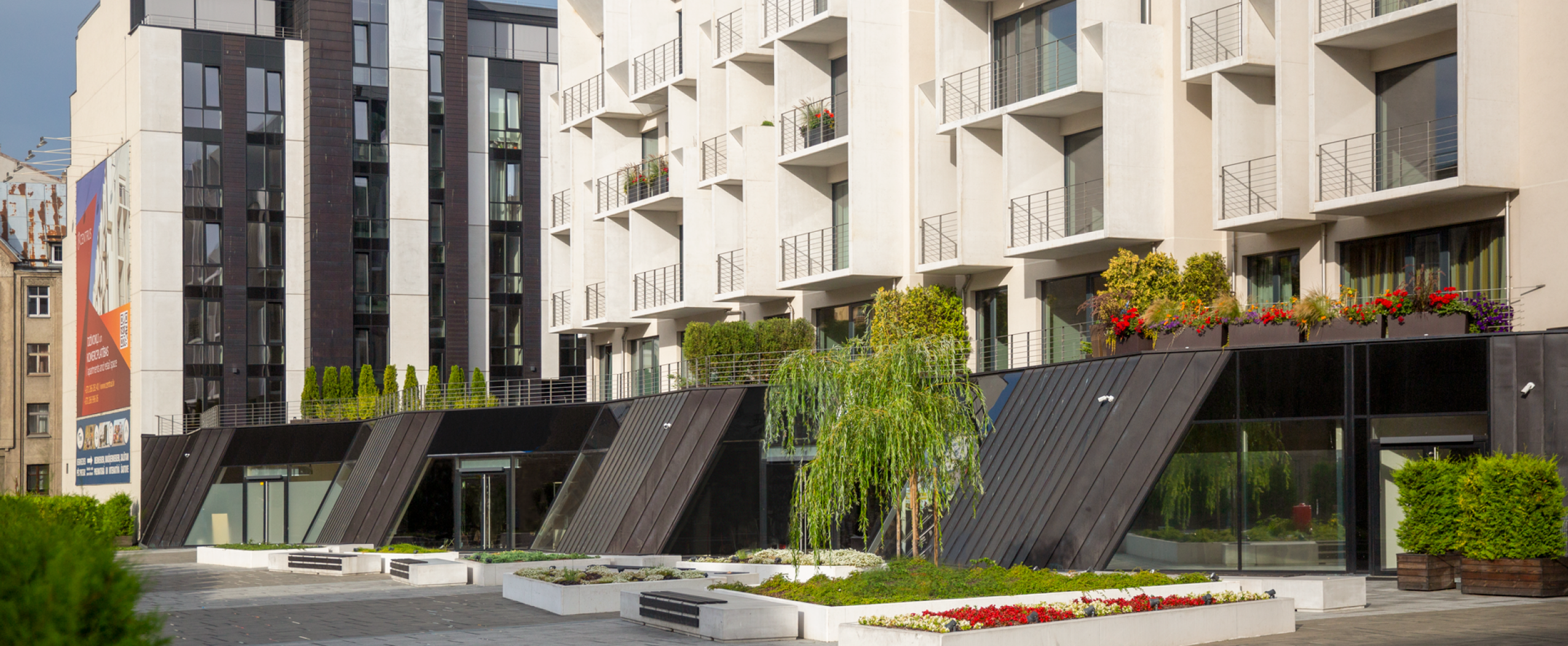 CENTRUS quarter promenade with trees, landscaping, and the first buildings visible in the background in the center of Riga.